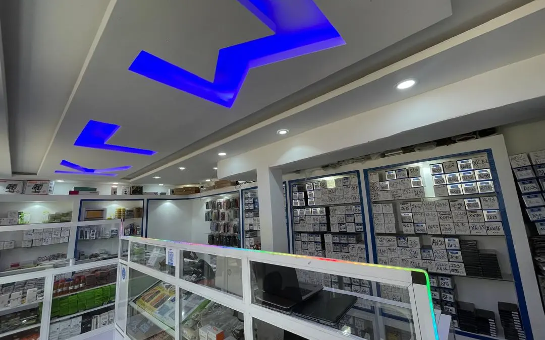 Intérieur de la boutique KLM-TECH : lettres KLM lumineuses au plafond, vitrines et mur de pièces de rechange étiquetées