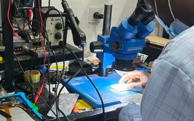 Technicien KLM-TECH au binoculaire, carte éclairée sous l'objectif